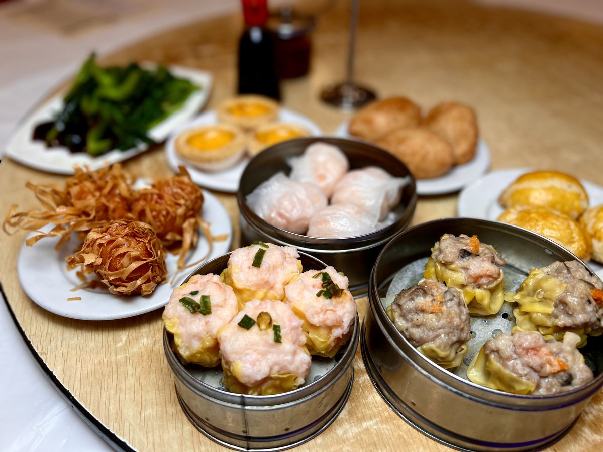 crispy shrimp balls, har gow, shu mai, egg tarts and more dishes fill a table at Crown Seafood.