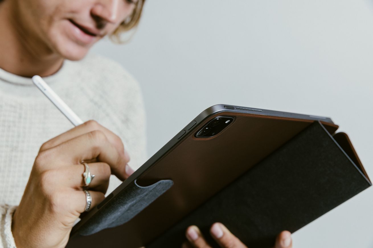 A person holding an iPad Pro in Nomad’s brown Leather Folio Plus case and writing on the screen using an Apple Pencil.