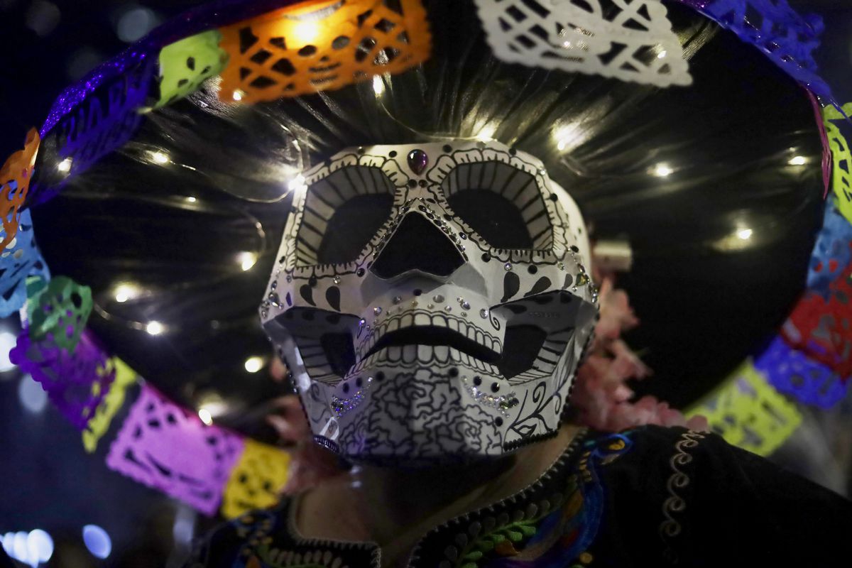 A woman in a skull mask and an elaborate hat.