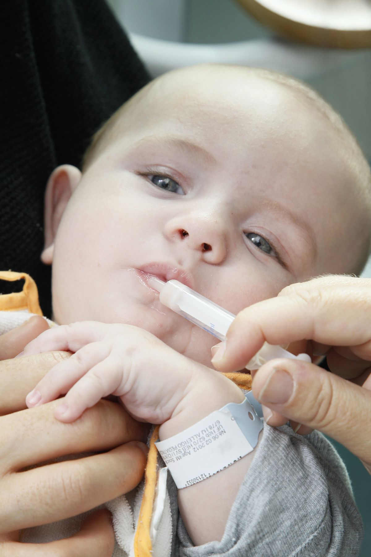 Photo of baby with syringe in its mouth.