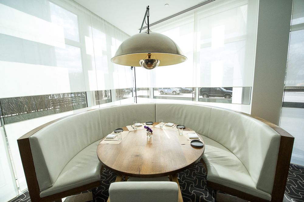 A round table with a light hanging overhead and window behind.