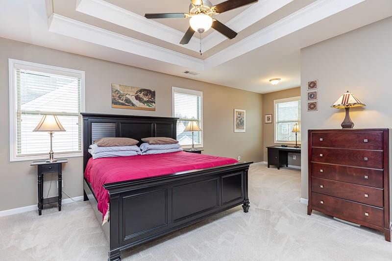 Large bedroom with king bed, nightstands and lamps, chest of drawers, and tray ceiling. 