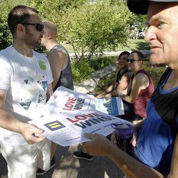 Carson Wagstaff passes out signs during a rally celebrating the Supreme Court's decision to legalize same-sex marriage at City Creek park in Salt Lake City on Friday, June 26, 2015.
