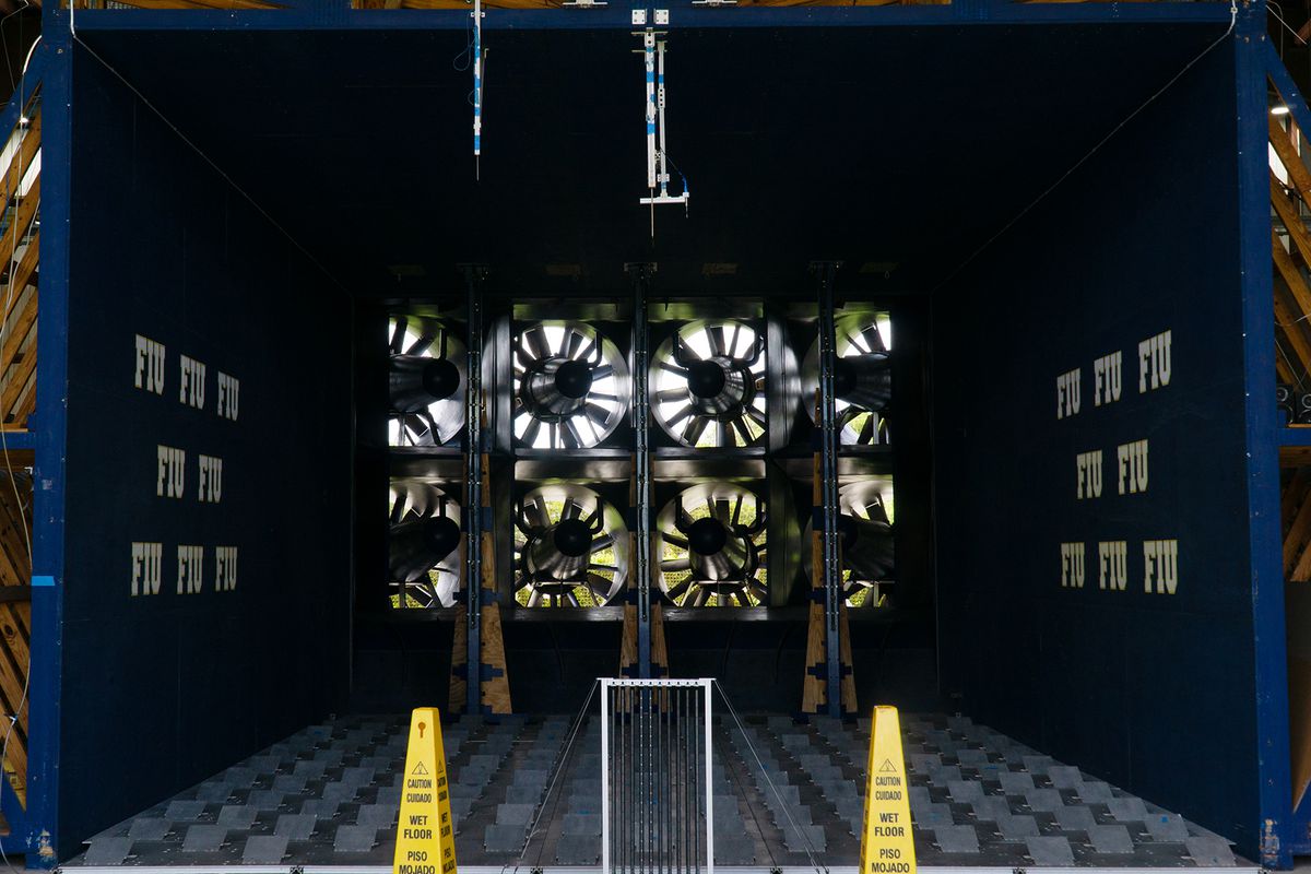 A view into a dark wind tunnel with several fans at the end.