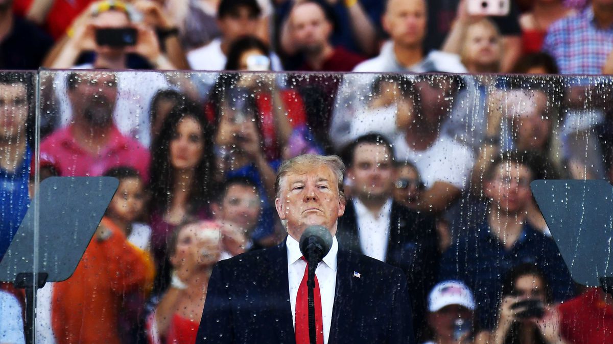 Trump, in a navy suit and bright red tie, scowls in front of a microphone. Behind him is bulletproof glass, wet from rain. And behind the glass, a crowd of cheering Trump supporters wearing red, white, and blue.