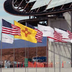 This Oct. 22, 2010 file photo shows U.S., New Mexico and Spaceport America flags fly at the edge of the uncompleted spaceport in Upham, N.M.   Sen. George Munoz has proposed legislation that calls for selling of the futuristic hangar, the nearly two-mile-long runway and the 18,000 acres that come with it.