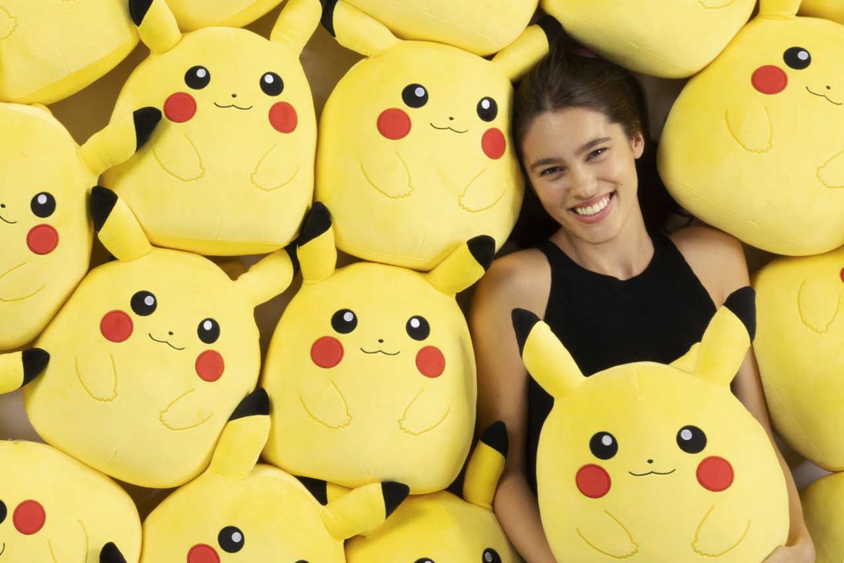 An image of a person laying in a bed of Pikachu Squishmallows.