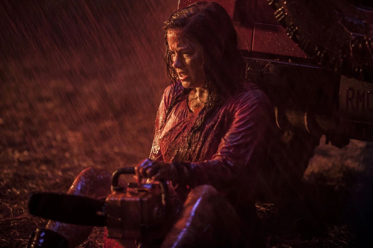 Jane Levy&nbsp;as Mia Allen holding a chainsaw while sitting on the ground, her clothes drenched in rain and viscera in 2013’s Evil Dead.