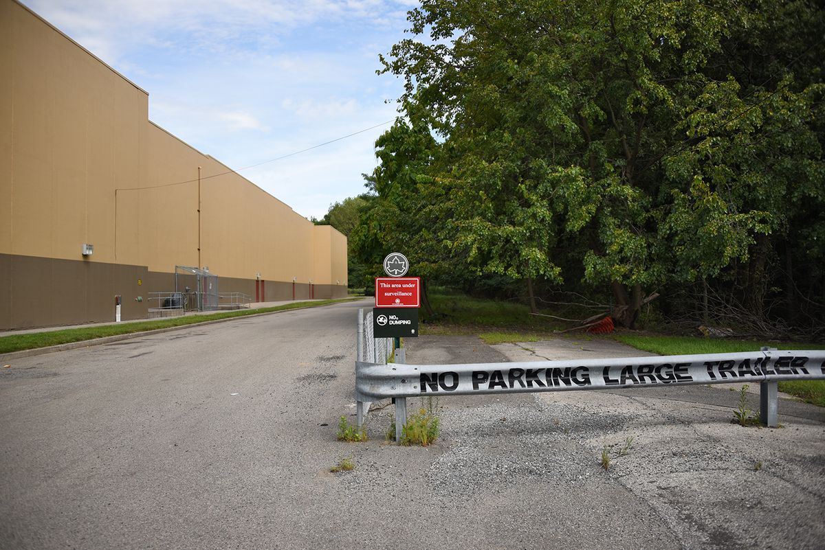 A parking lot with a steel beam that says “No Parking Large Trailer” situated in the middle. 