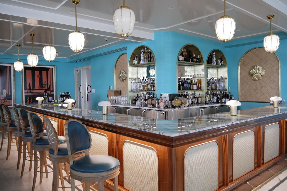 Indoor bar with blue tables and brown bar area with turquoise wall