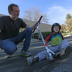 Jon Owen assists his son Ben with a scooter near their home on Thursday, Oct. 30, 2014, in Salt Lake City. Ben was diagnosed with autism spectrum disorder at age 2. Jon is president of the Utah Autism Coalition.