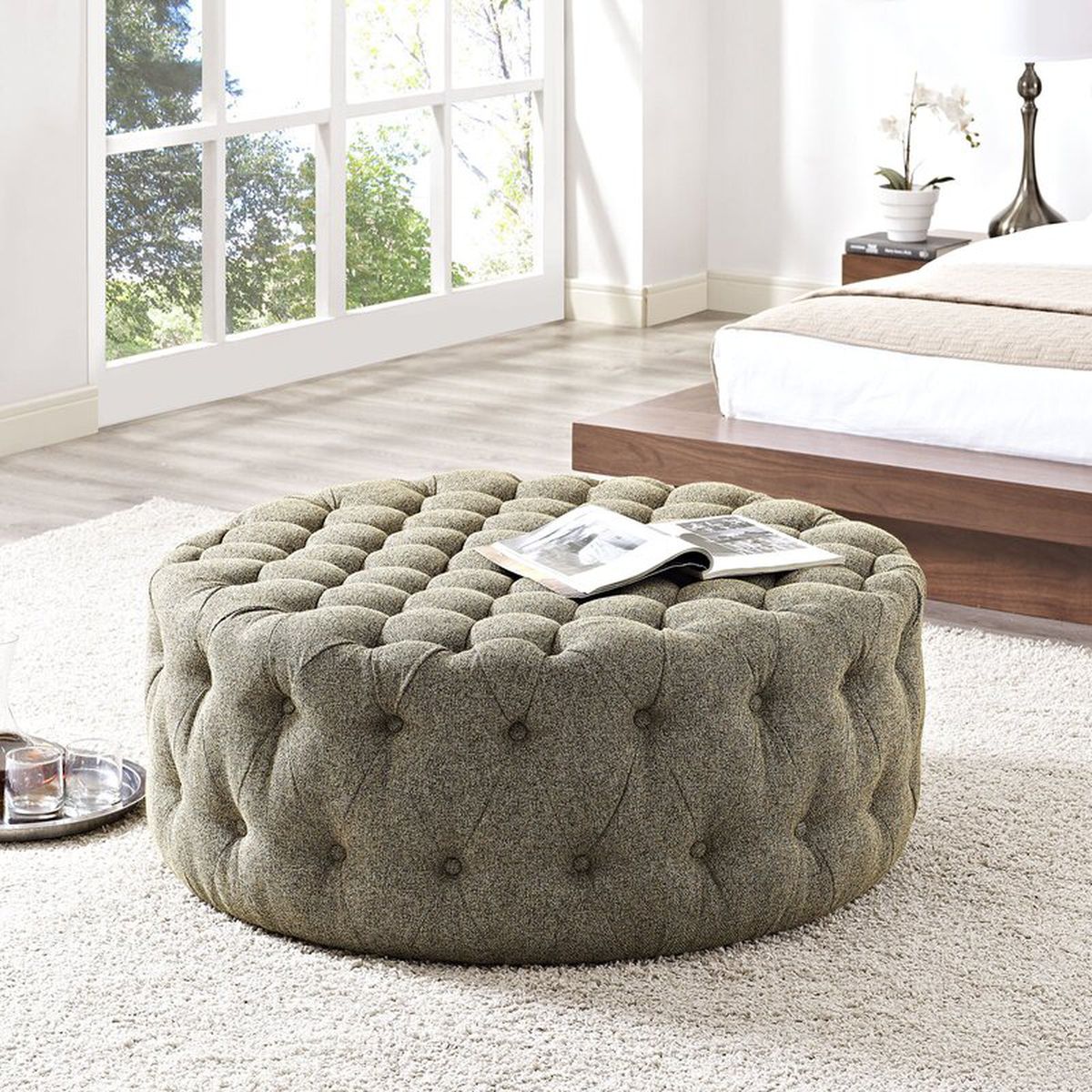 Gray round tufted ottoman in a bedroom.