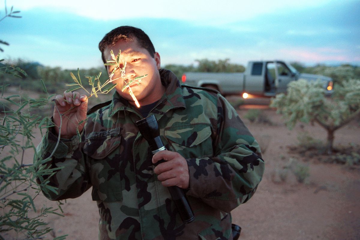 A Native American patrol officer looks at a fiber left on the end of a plant to see if it's clothing or part of bags often used to transport marijuana.