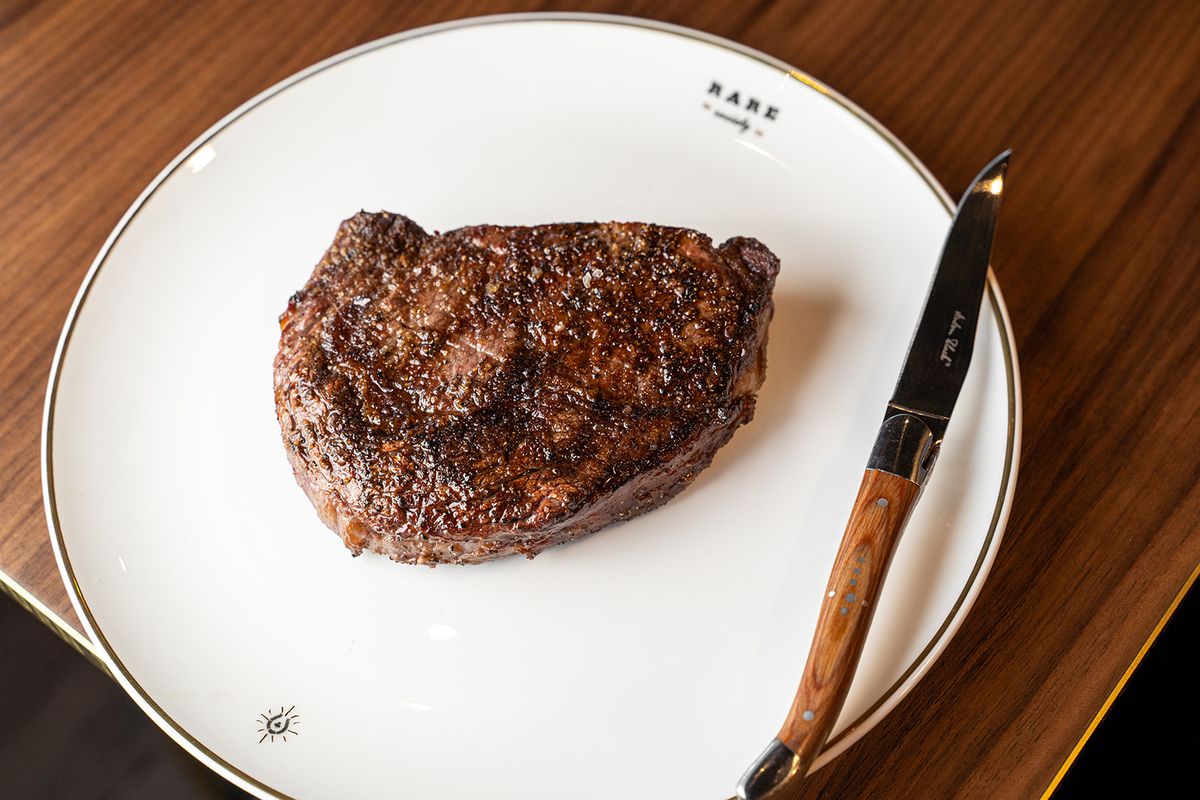 A 16-ounce cooked ribeye steak on a white plate.