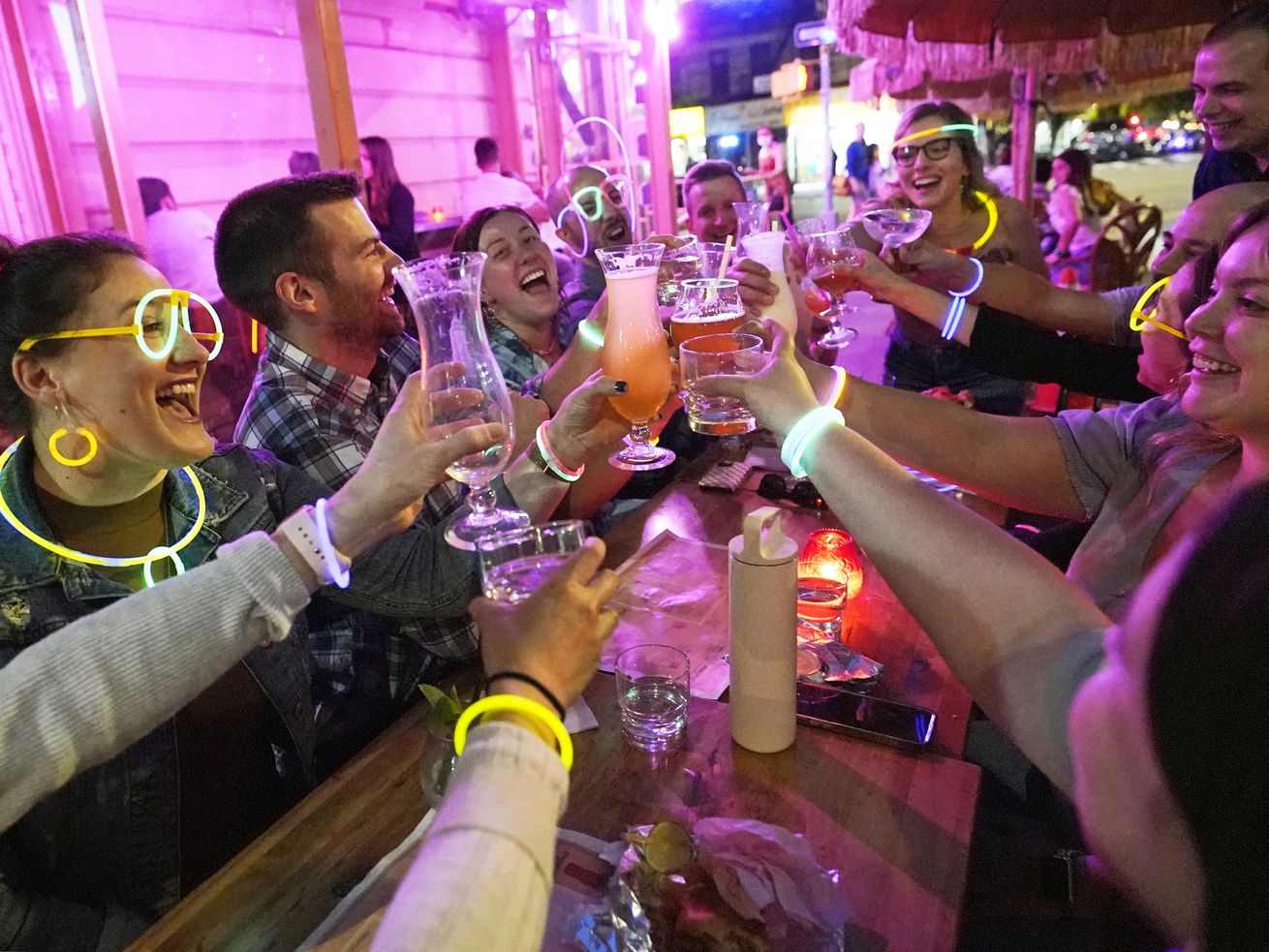 Emily Baumgartner, left, and Luke Finley, second from left, join friends from their church group in a birthday toast to one of the members, upper right, during their weekly “Monday Night Hang” gathering at the Tiki Bar on Manhattan’s Upper West Side Monday, May 17, 2021, in New York.