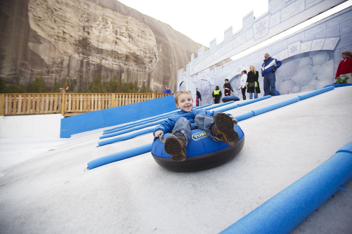 Child snow tubing with Stone Mountain in the background.