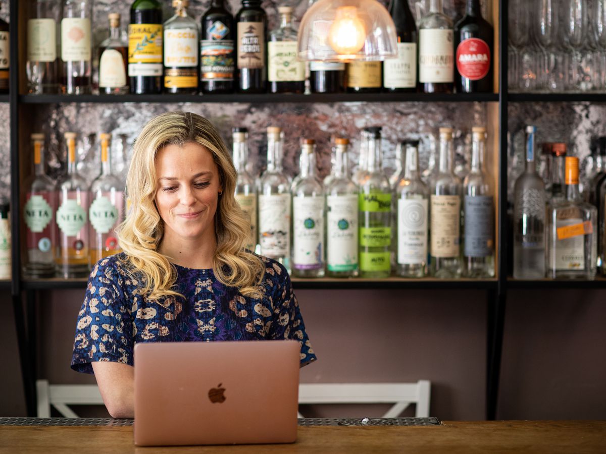 A woman uses a laptop at a restaurant bar