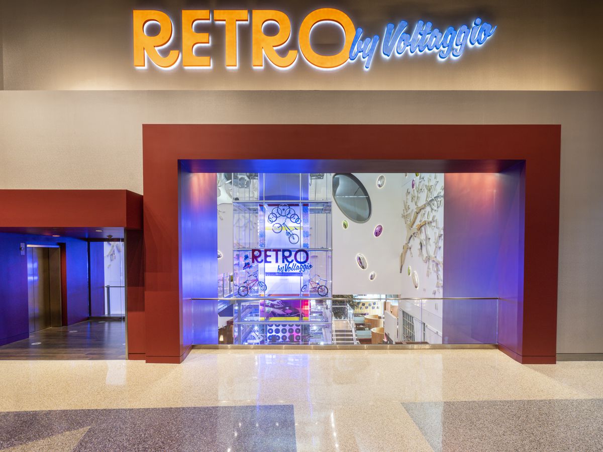 The word “retro” in all caps and orange letters beside “by Voltaggio” written in blue cursive above an open doorway.