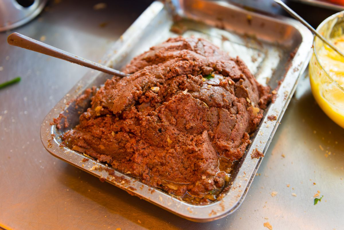 A mound of pate in a serving tray with a spoon sticking out.