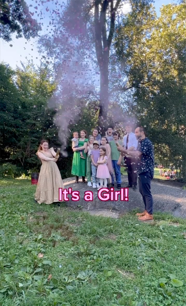 A large family has a gender reveal party in a park. Text reads, “It’s a Girl!”