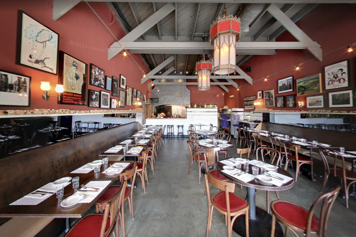 A red restaurant with wooden tables and tall ceilings at daytime.