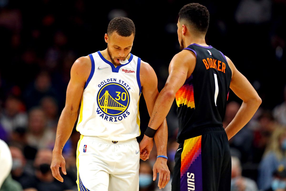 Golden State Warriors guard Stephen Curry (30) reacts with Phoenix Suns guard Devin Booker (1) during the first quarter at Footprint Center.