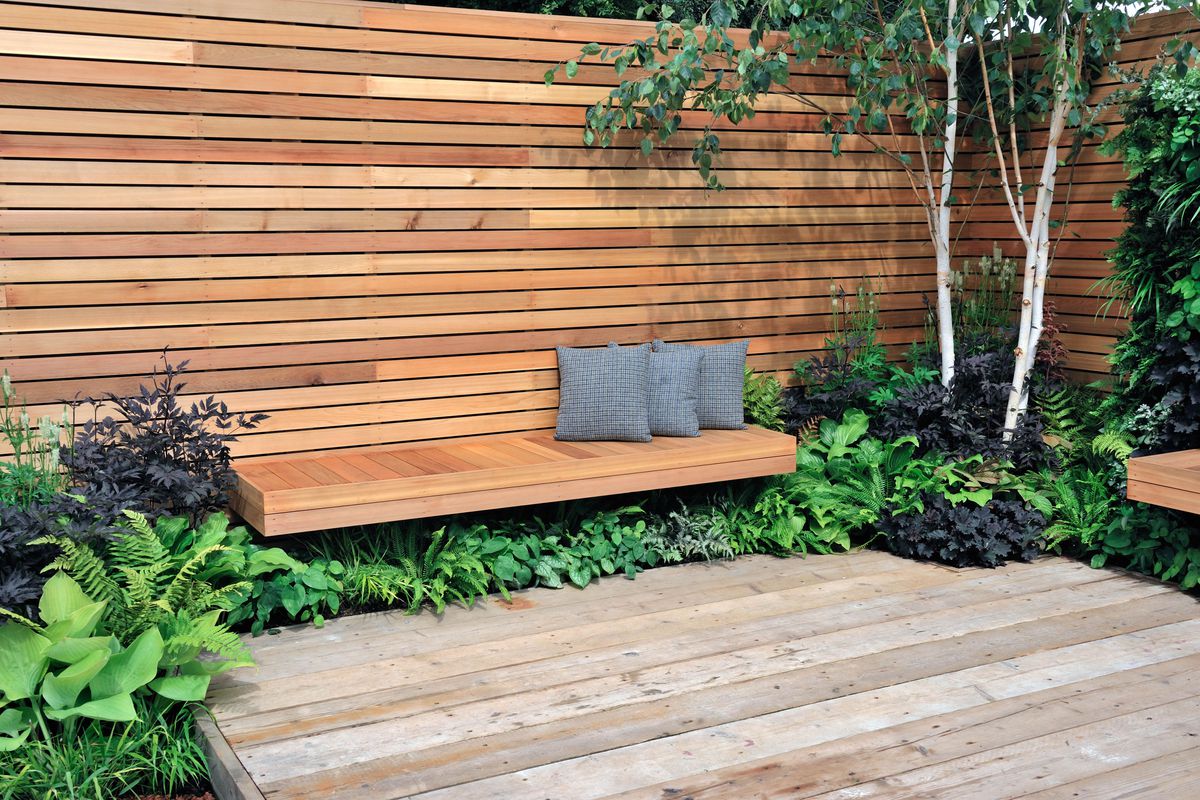 A floating deck that has a tall privacy fence and wood benches