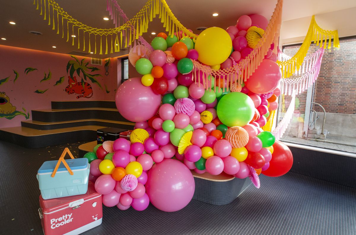 A floor-to-ceiling abstract balloon sculpture in pink, green, yellow, and orange