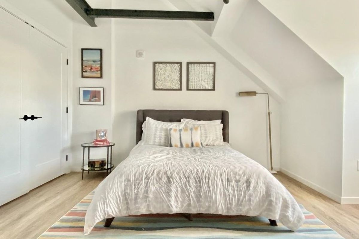 The bedroom area of a studio, with an arched ceiling with exposed beams and a bed.