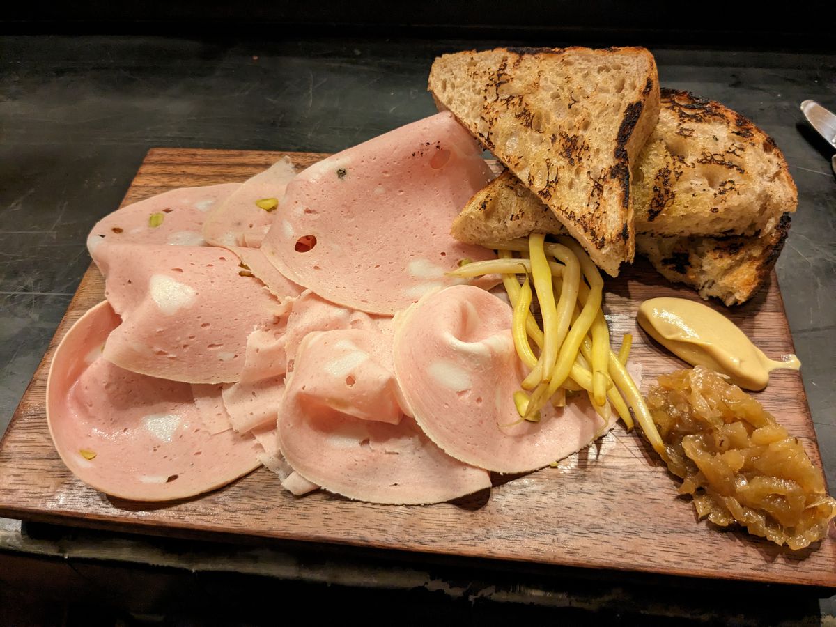 A plate of mortadella, mostarda, yellow beans, and toast.