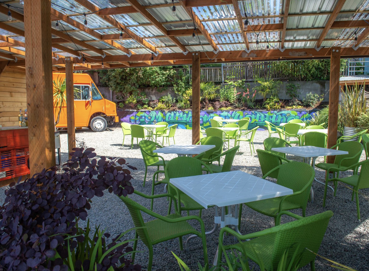 The downstairs patio at Agua Verde, with a bright orange food truck in the background.