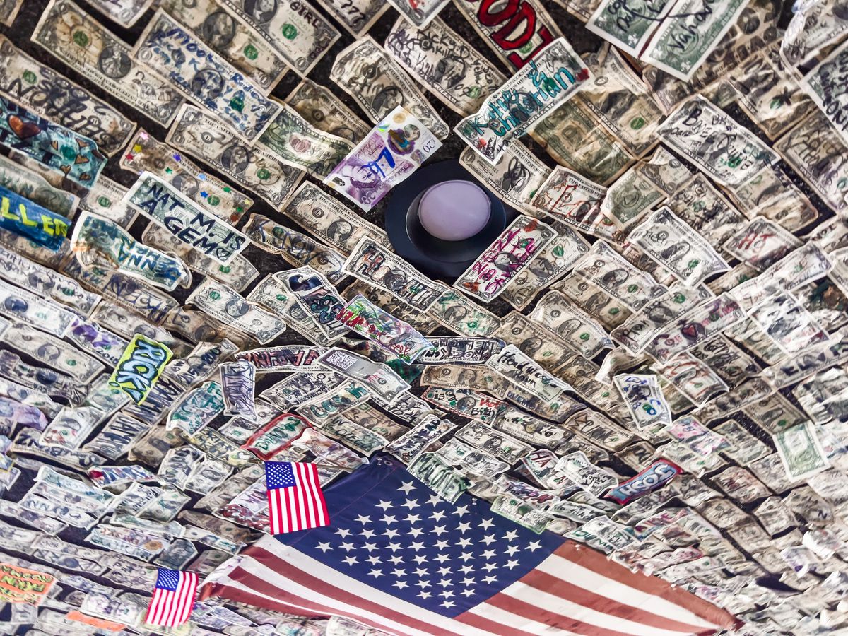 A dive bar with American flag surrounded by signed dollar bills.