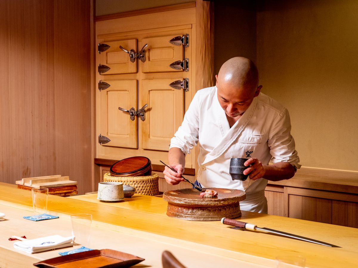 Chef Nozomu Abe brushes a slice of fatty tuna sushi with a soy reduction.