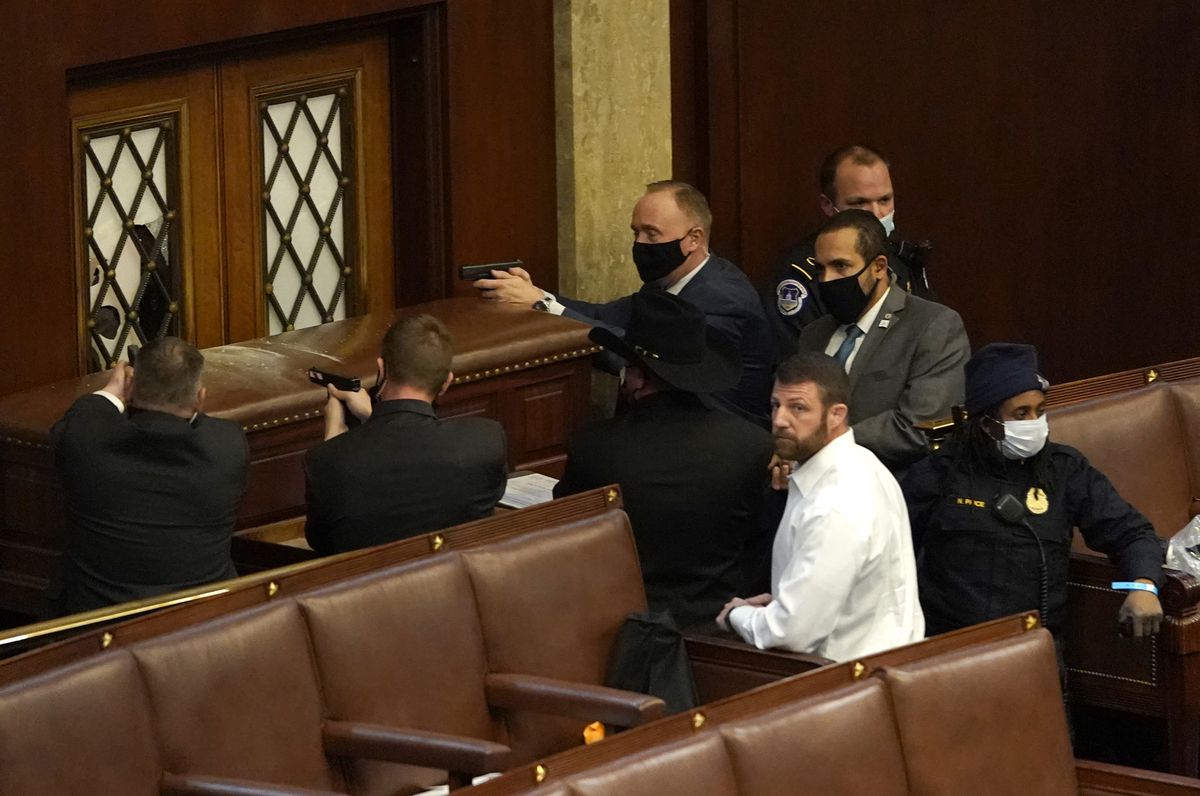 U.S. Capitol police officers draw their guns as an intruder attempts to break through a barricaded door to the House Chamber.