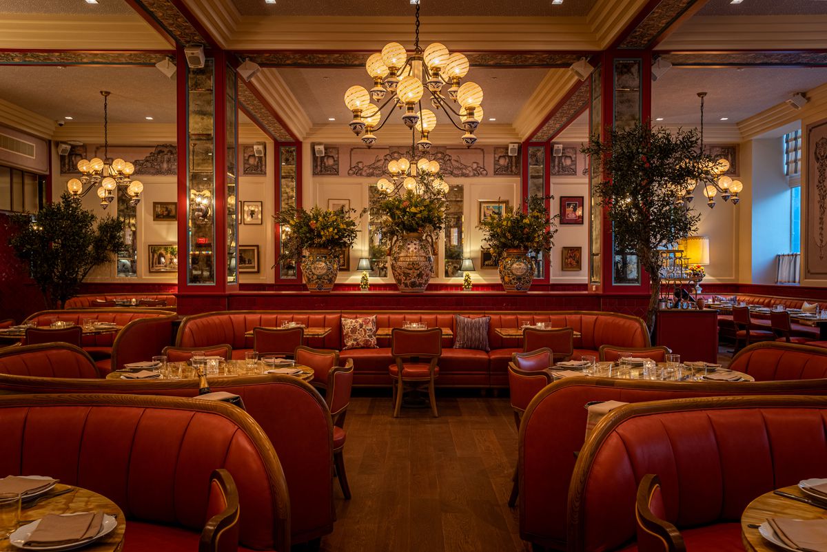 A wide angle view of a deep red restaurant dining room with vintage touches, at night.