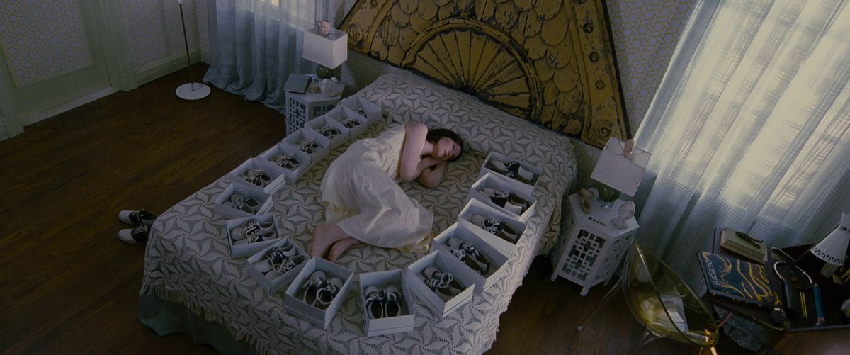 Mia Wasikowska as India Stoker, lying on her bed surrounded by boxes of identical black and white shoes in Stoker.