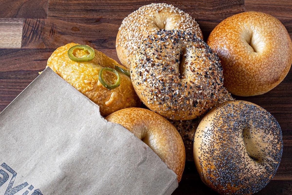 A bunch of bagels being spilled form a paper bag.
