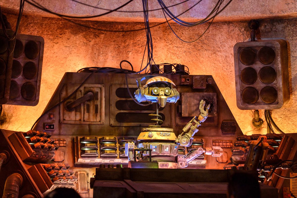 The droid R-3X waves from a console at Galaxy’s Edge