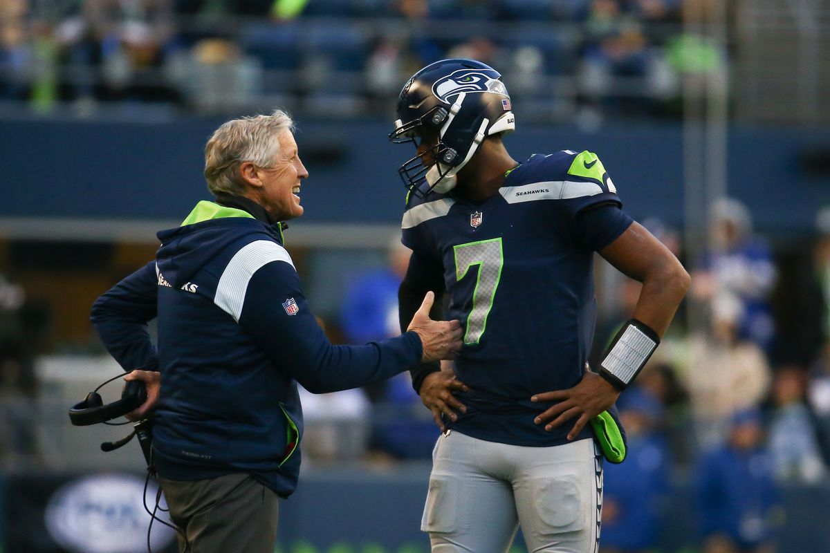 Geno Smith #7 of the Seattle Seahawks talks with head coach Pete Carroll in between plays against the New York Jets during the second half of the game at Lumen Field on January 1, 2023 in Seattle, Washington.
