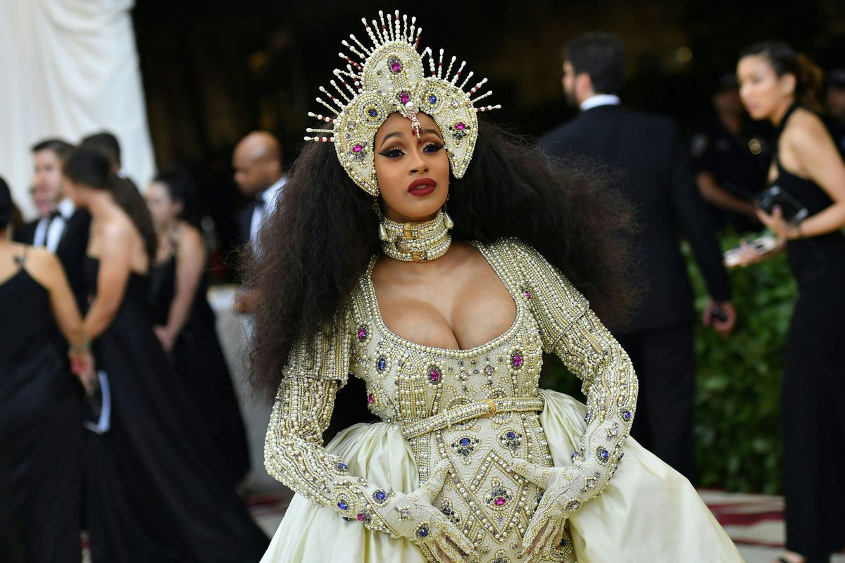 Cardi B wears a huge butter-yellow gown and a jeweled headpiece.