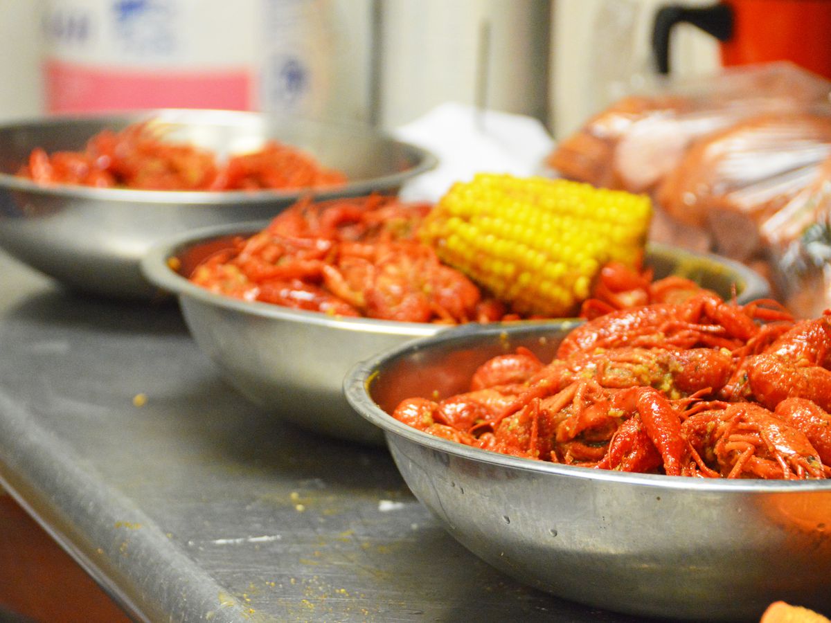 Three silver bowls filled of steamy crawfish and boiled corn on the cob at Crawfish &amp; Noodles.