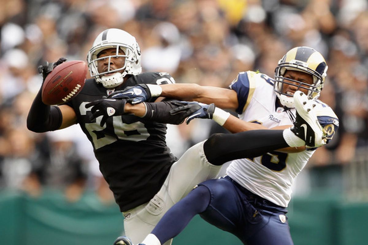 Stanford Routt #26 of the Oakland Raiders intercepts a pass intended for Laurent Robinson #19 of the St. Louis Rams.
