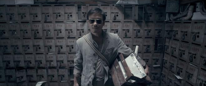 Image from Rigor Mortis, showing a man wearing sunglasses, holding a box, and surrounded by safety deposit boxes.
