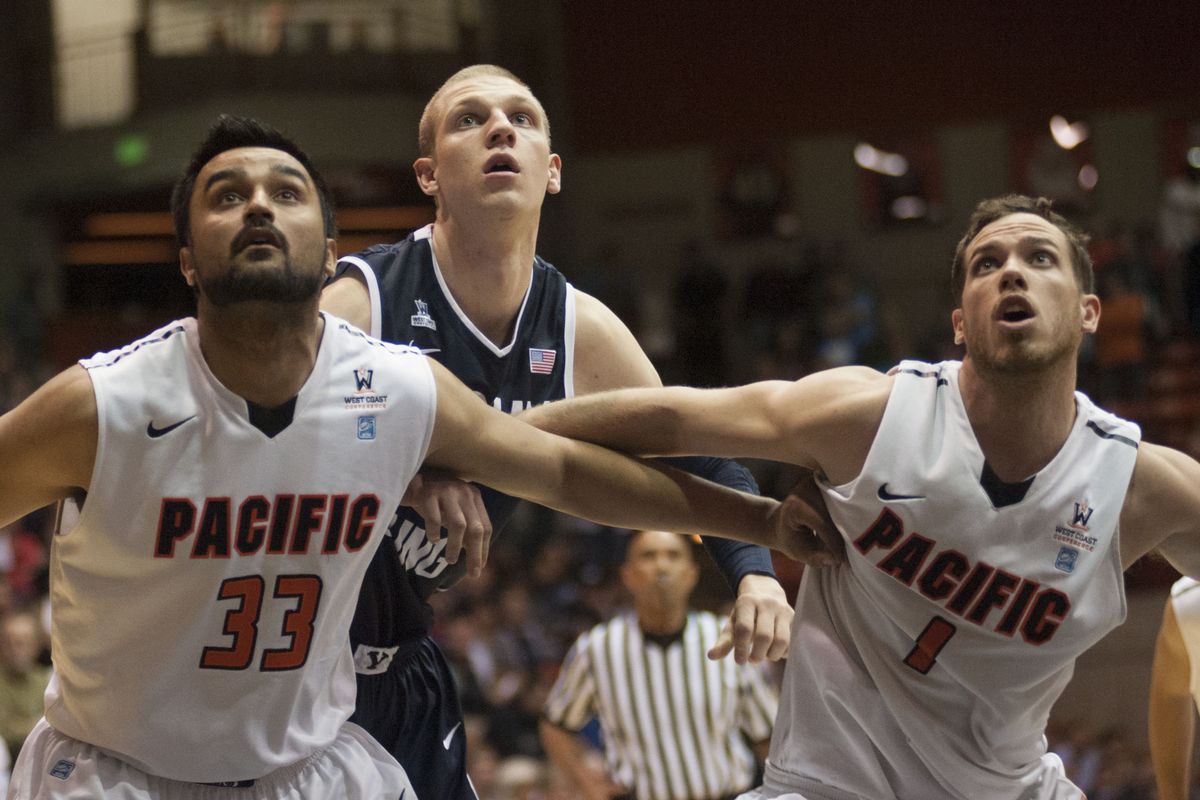 Pacific's Tony Gill (33) and Trevin Harris (1) box out BYU forward Nate Austin.