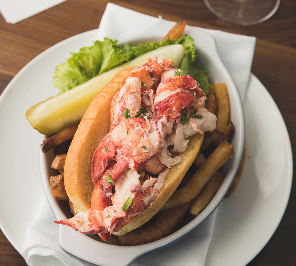 From above, a lobster roll overloaded with claw meat, on a bed of french fries.