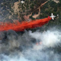 An aircraft lays down a line of fire retardant between a wildfire and homes in the dry, densely wooded Black Forest area northeast of Colorado Springs, Colo., Thursday, June 13, 2013.  More than 350 homes have been lost in what is now the most destructive wildfire in Colorado history, surpassing last year's Waldo Canyon fire, which burned 347 homes, killed two people and led to $353 million in insurance claims. (AP Photo/John Wark)