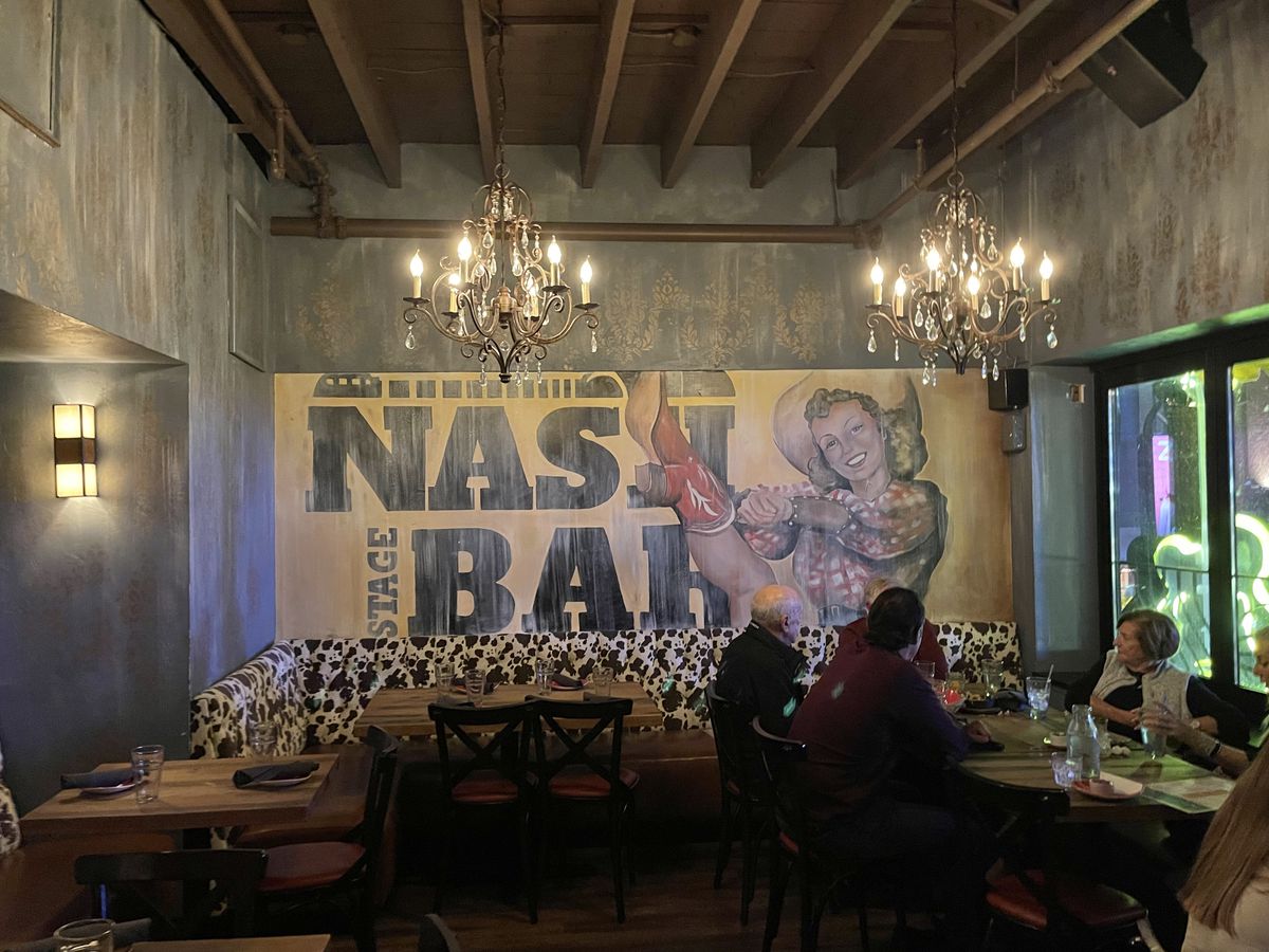 A large poster advertising Nash Bar with a dancing cowgirl.