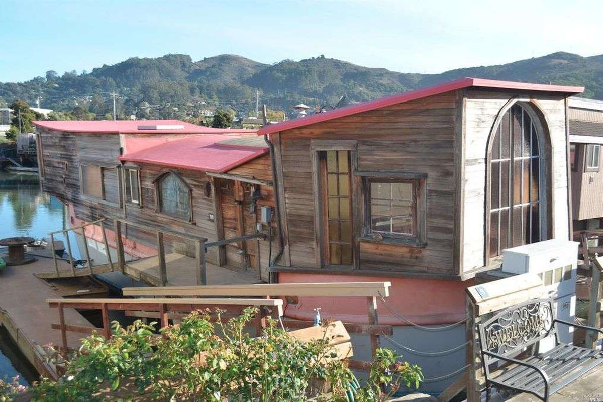 A houseboat with uneven additions built onto both sides.