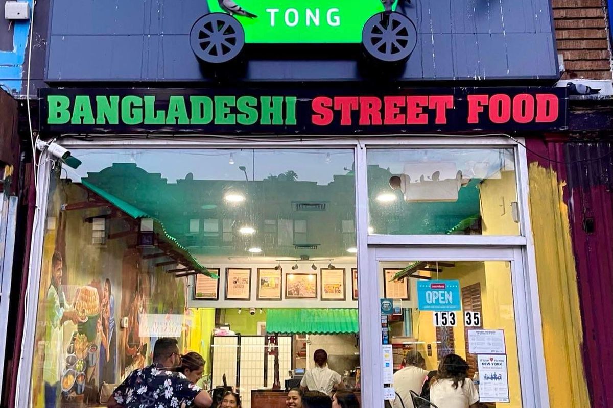 An awning shows an illustration of a green street cart and spells out “Bangladeshi Street Food” in a packed restaurant