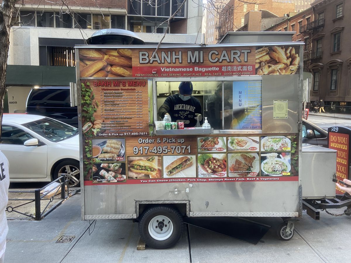 A metal truck with signs for Vietnamese dishes is park on Hanover Square.